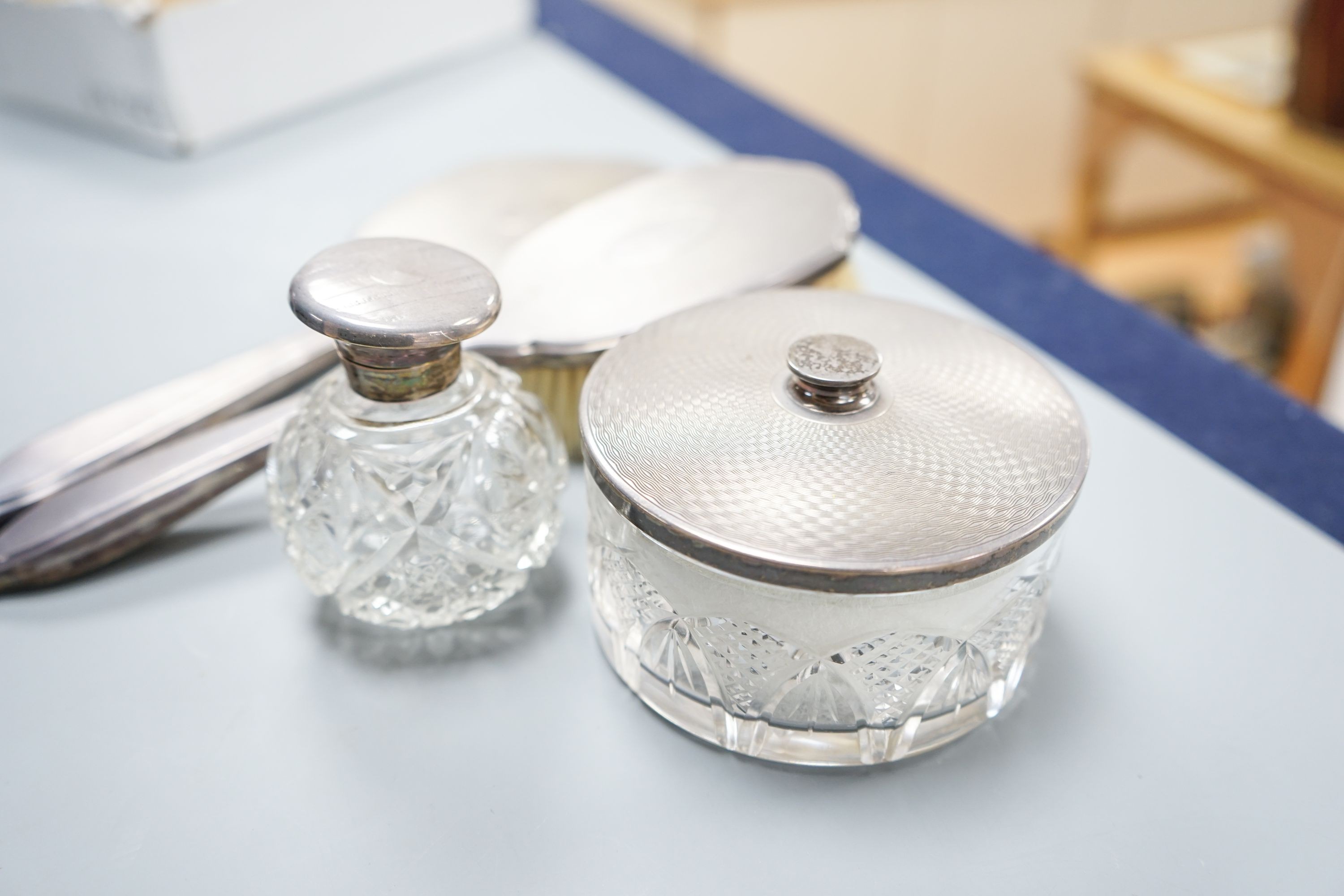 A silver-backed hand mirror and hairbrush, a silver-mounted scent bottle and a powder bowl.